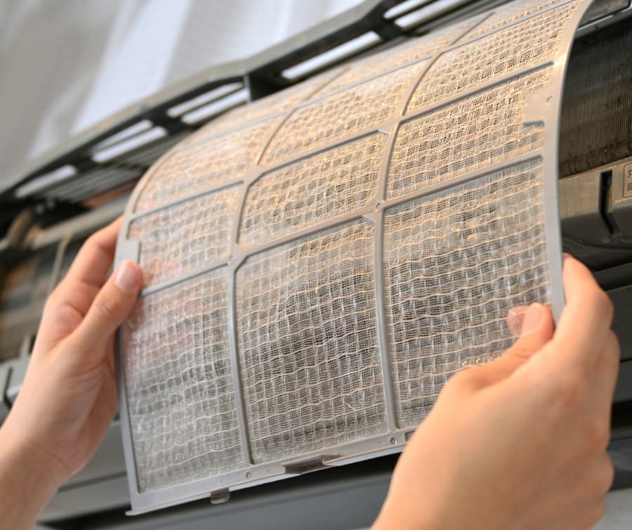 Homeowner removing and replacing air filter for ductless AC system